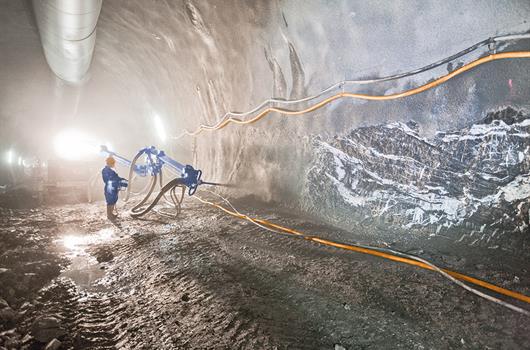 Stavební pracovník stříká beton strojem v tunelu
